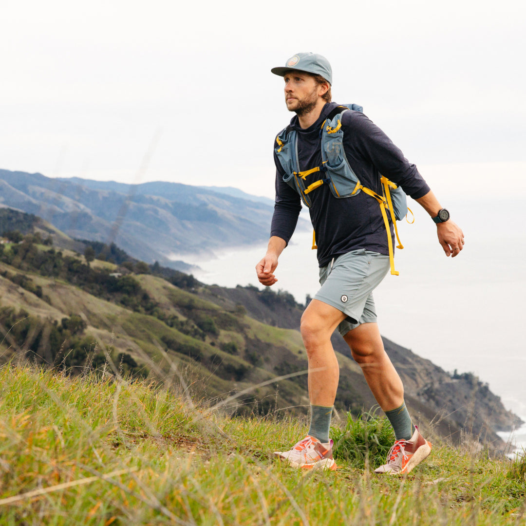 Model walk up a grassy hill wearing the 1972 Light Hiker micro crew hiking sock in seafoam