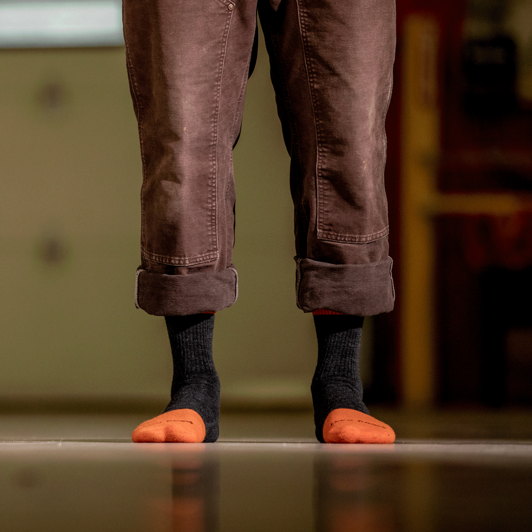 Worker in work pants showing men's steely micro crew socks in graphite black and orange