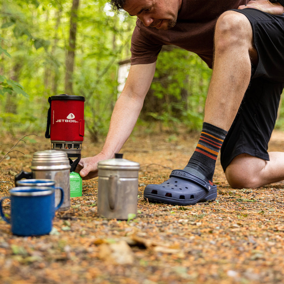 Close up shot of model setting up food at a campsite wearing the men's fastpack micro crew hiking socks in charcoal