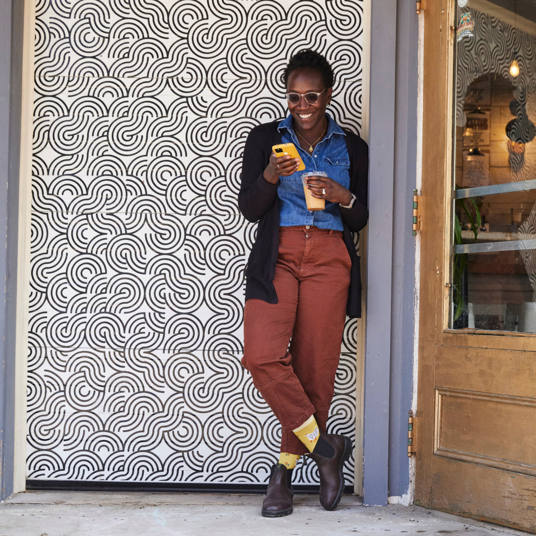 model leaning against an outside wall with feet crossed wearing the 6114 Sunny