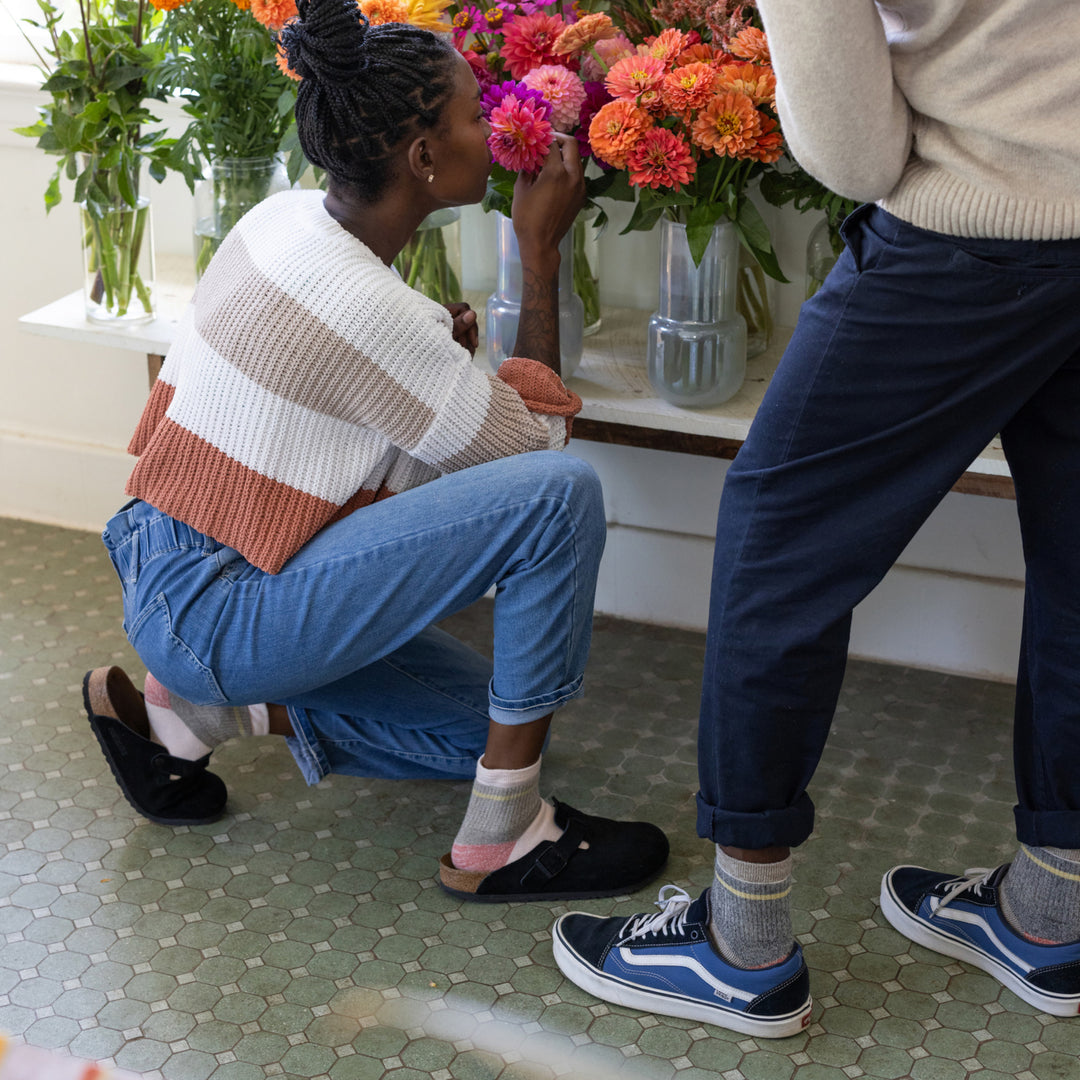 model kneeling down to smell flowers wearing Clogs and the 6117 Dusty Rose