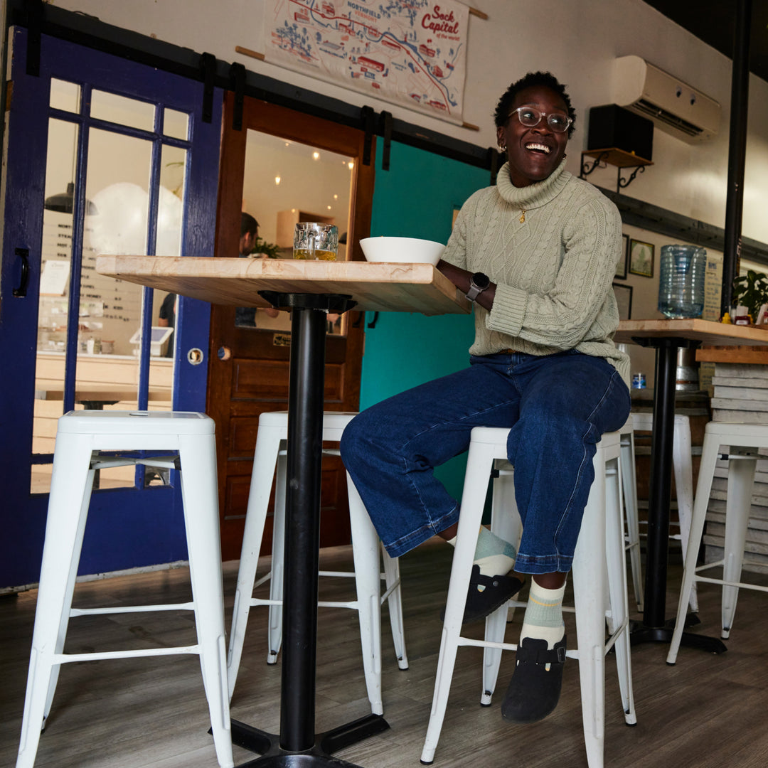 Model sitting at table on a stool wearing the 6117 Pear in clogs