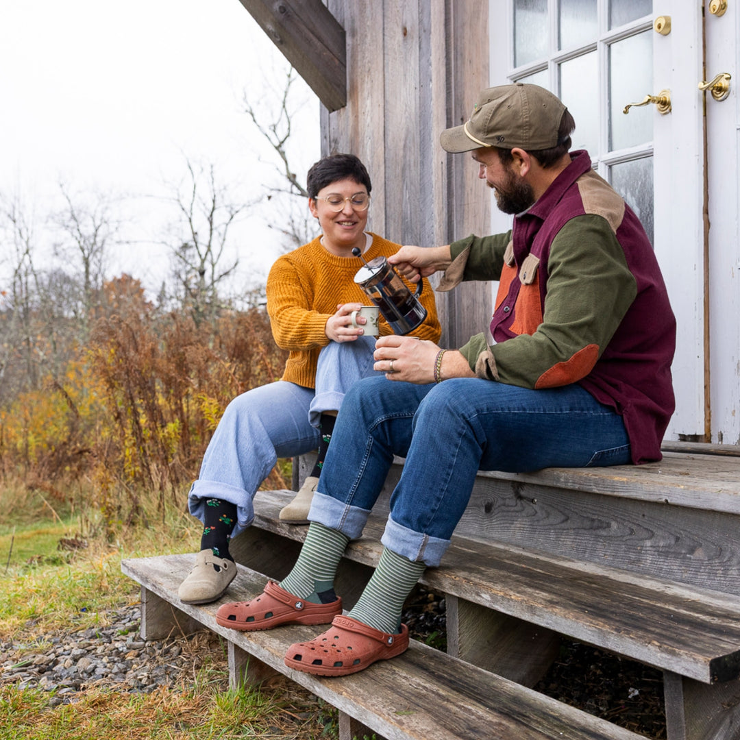 image of man and woman sitting on wood stairs pouring coffee man wearing 6134 microstripe crew lightweight moss sock