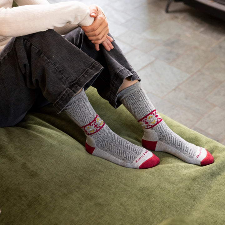 close up image of models feet posed on green couch cushion wearing 6141 nordic twist crew lightweight with cushion ash sock