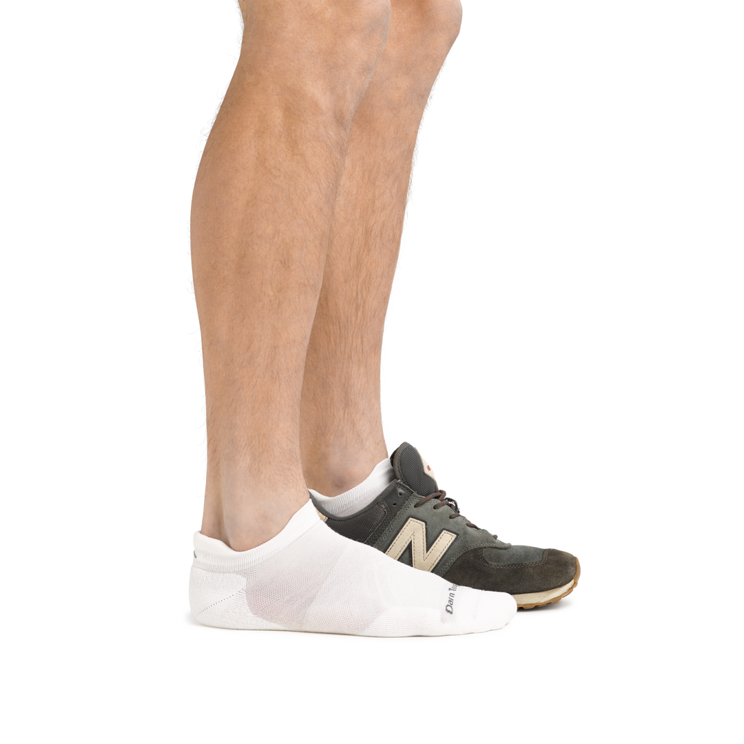 Profile of male legs facing right, front foot wearing Run No Show Tab Ultralightweight Running Socks in White and the back foot also wearing an athletic sneaker