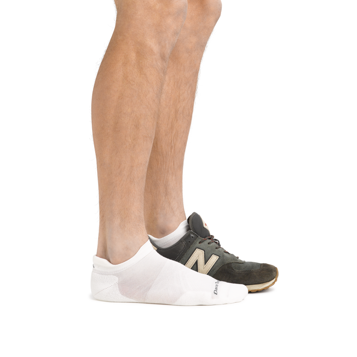 Profile of male legs facing right, front foot wearing Run No Show Tab Ultralightweight Running Socks in White and the back foot also wearing an athletic sneaker