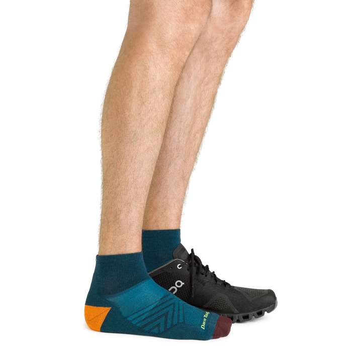 Side shot of model wearing the men's quarter running sock in dark teal with a black sneaker on his left foot