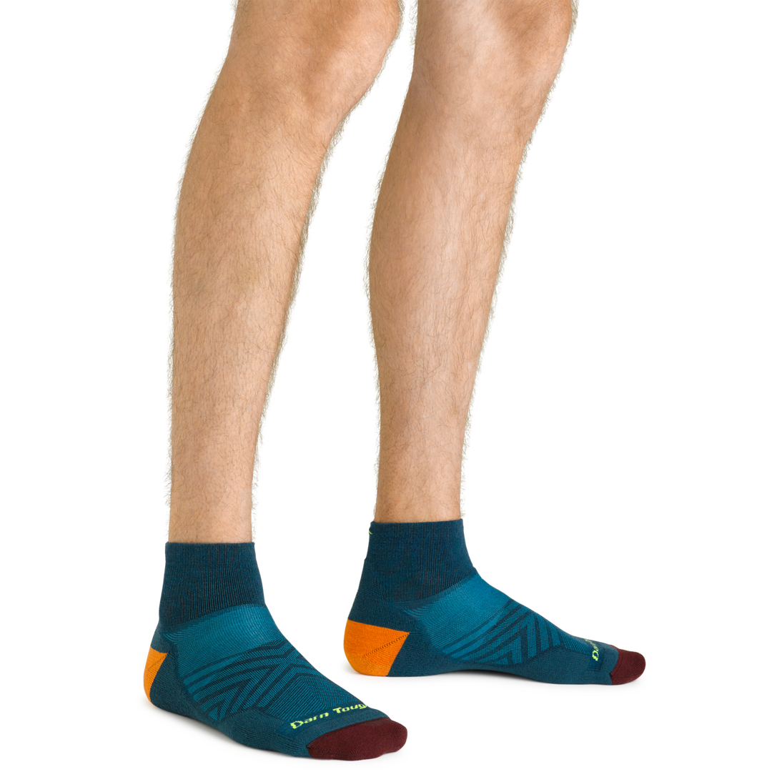 Close up shot of model wearing the men's quarter running sock in dark teal with no shoes on