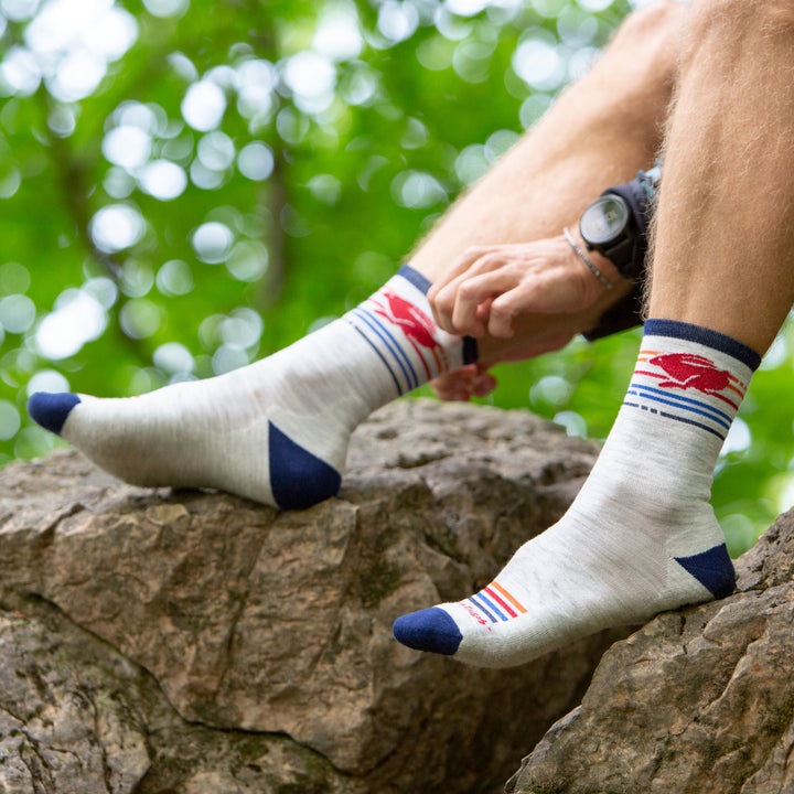 Man sitting on a rock barefoot wearing Pacer Micro Crew Ultra-Lightweight Running Sock in Ash
