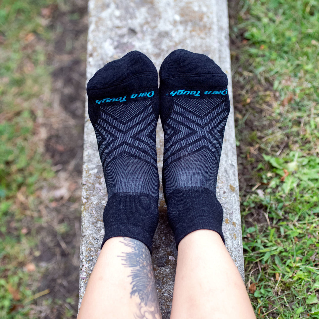 Close up image of a woman's feet on a rock wearing Women's Run Quarter Ultra-Lightweight Running Socks in Black, Lifestyle Image