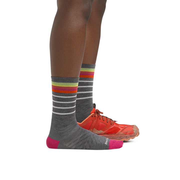 Woman wearing Women's Stride Micro Crew Ultra-Lightweight Running Sock in Gray with one foot also in a running shoe