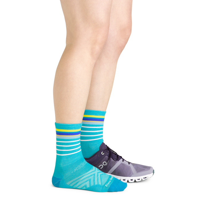 Side shot of model wearing the women's stride micro crew running sock in teal with a purple shoe on her left foot