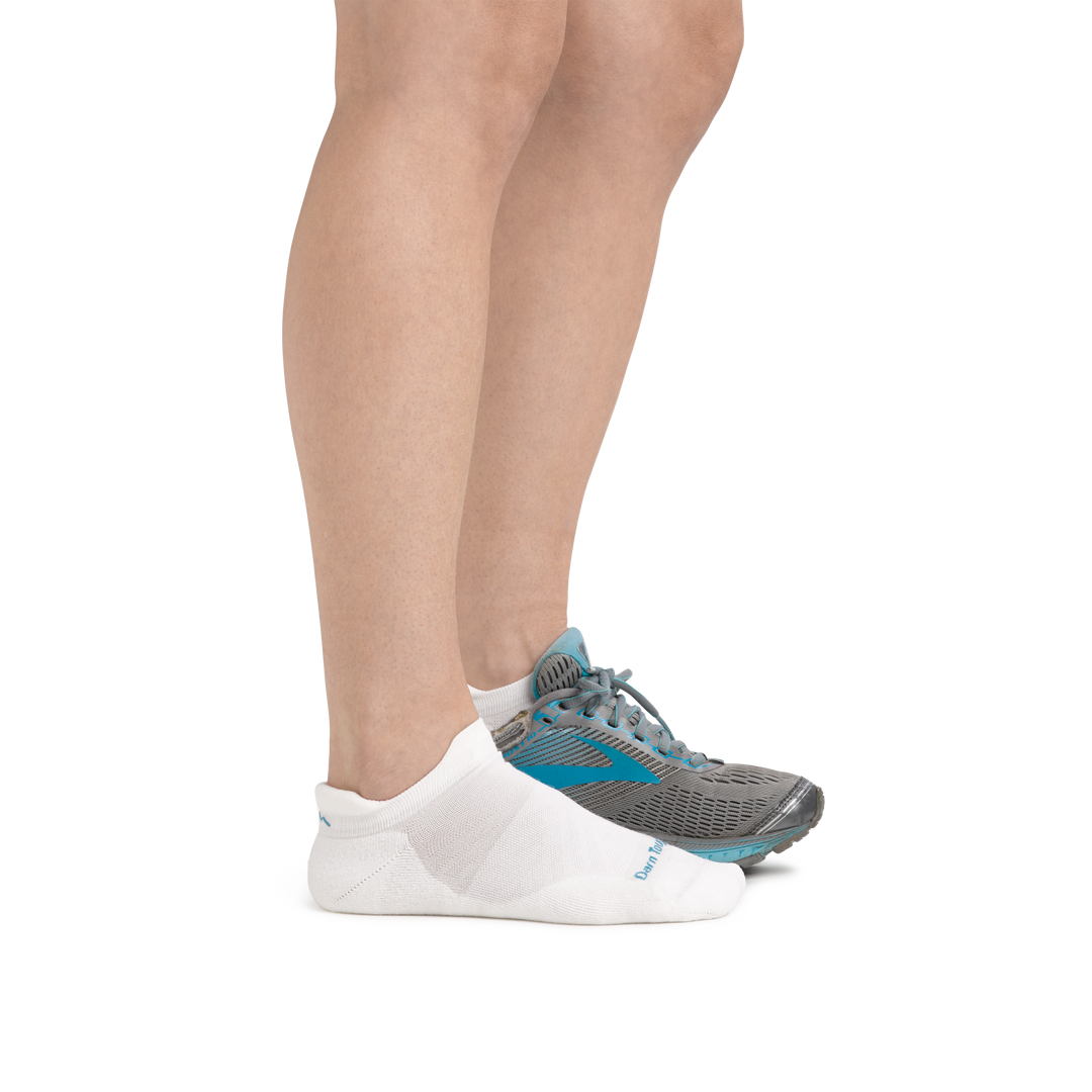 Profile image of a woman's legs, facing right on a white background, wearing Women's Run No Show Tab Ultra-Lightweight Running Socks in White and a running shoe on one foot