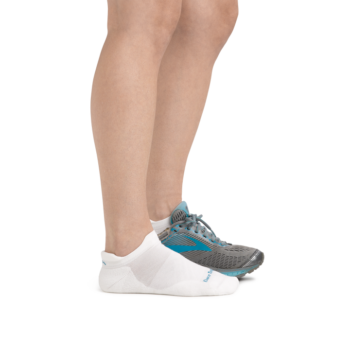 Profile image of a woman's legs, facing right on a white background, wearing Women's Run No Show Tab Ultra-Lightweight Running Socks in White and a running shoe on one foot