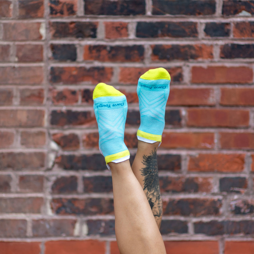 Woman's legs up in the air in front of a brick wall wearing Women's Run Coolmax No Show Running Socks in Aqua