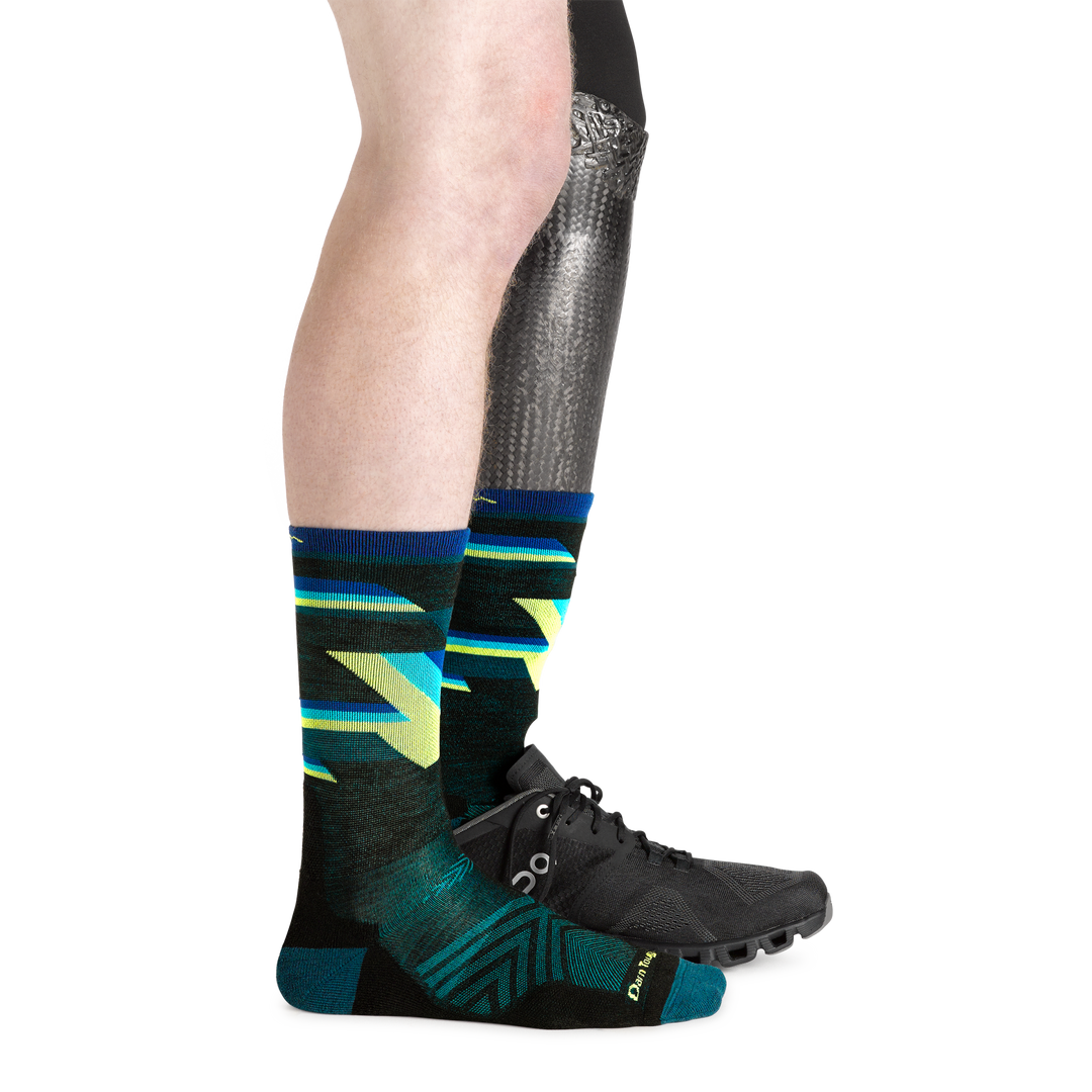 1056 men's bolt micro crew running socks in black on model with prosthetic leg wearing running shoe on left foot