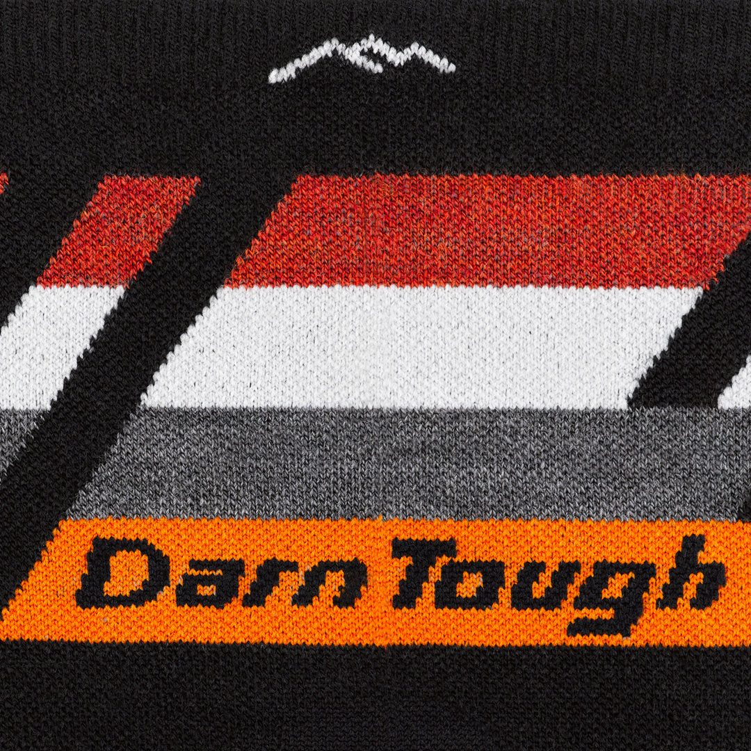 Call out detail image of the of the 1061 Black Front image of darn tough logo with orange background with red/white/gray stripe