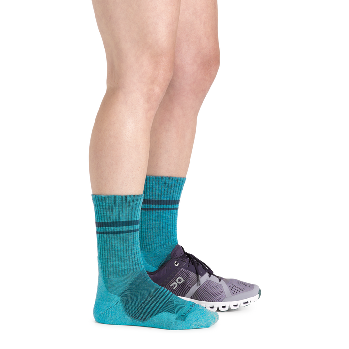 Side studio shot of model wearing women's element micro crew running sock in cyan with purple sneaker on left foot
