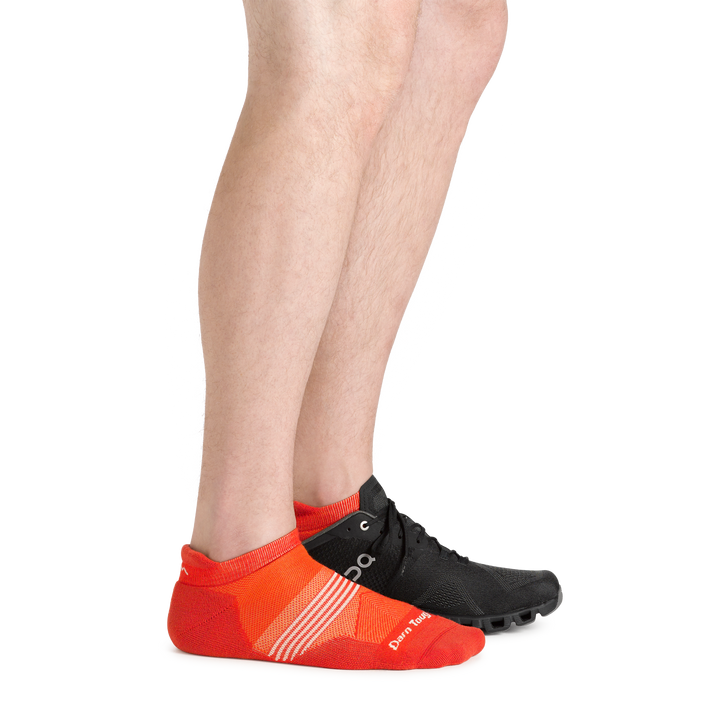  Side shot of model wearing the men's element no show tab running sock in tiger color with a black sneaker on his left foot