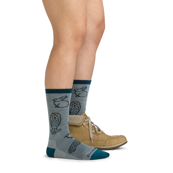 Image of model wearing 1678 Woodland Creatures Lifestyle Socks in Seafoam colorway and brown leather boot on one foot
