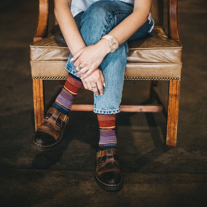 Woman sitting in an old leather and wood chair wearing shoes and Women's Pixie Crew Lightweight Lifestyle Socks in Navy