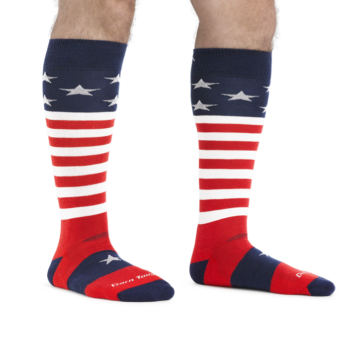 Man standing barefoot wearing Captain Stripe Over the Calf Ski & Snowboard Socks in Stars and Stripes pattern