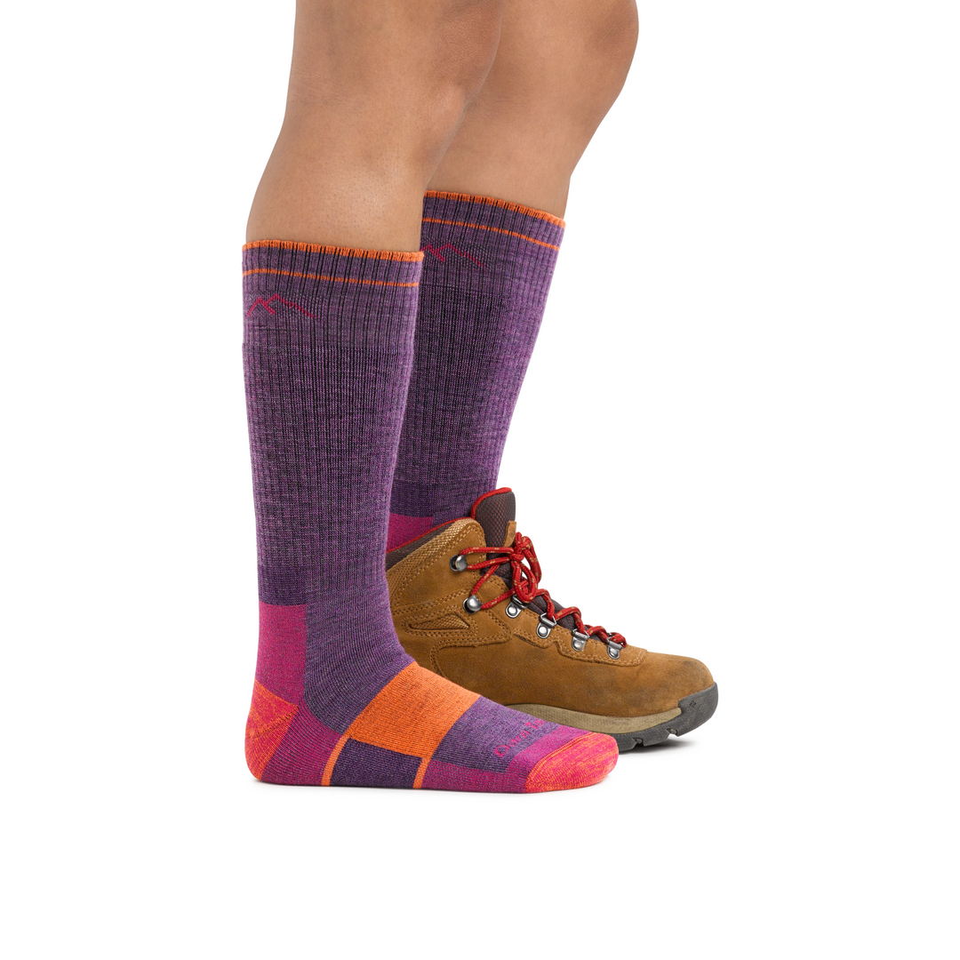 Studio shot of model wearing hiker boot socks in Plum Heather and one brown boot, showing the sock's tall height.
