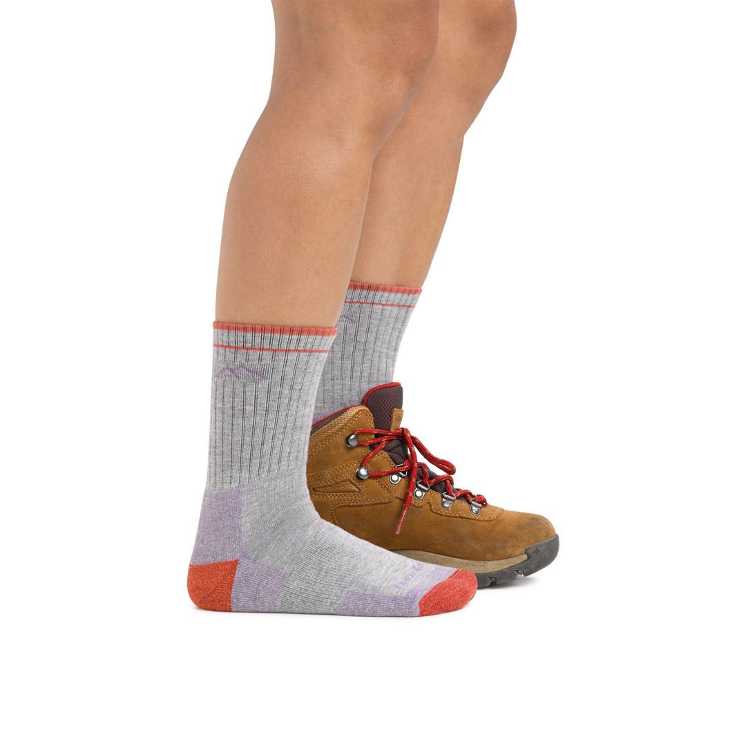 Woman wearing Coolmax Hiker Micro Crew Midweight Hiking Socks in Light Gray with one hiking boot on the back foot