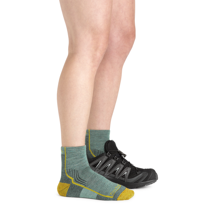Woman wearing Women's Hiker Quarter Midweight Hiking Socks in sage and a hiking shoe on one foot