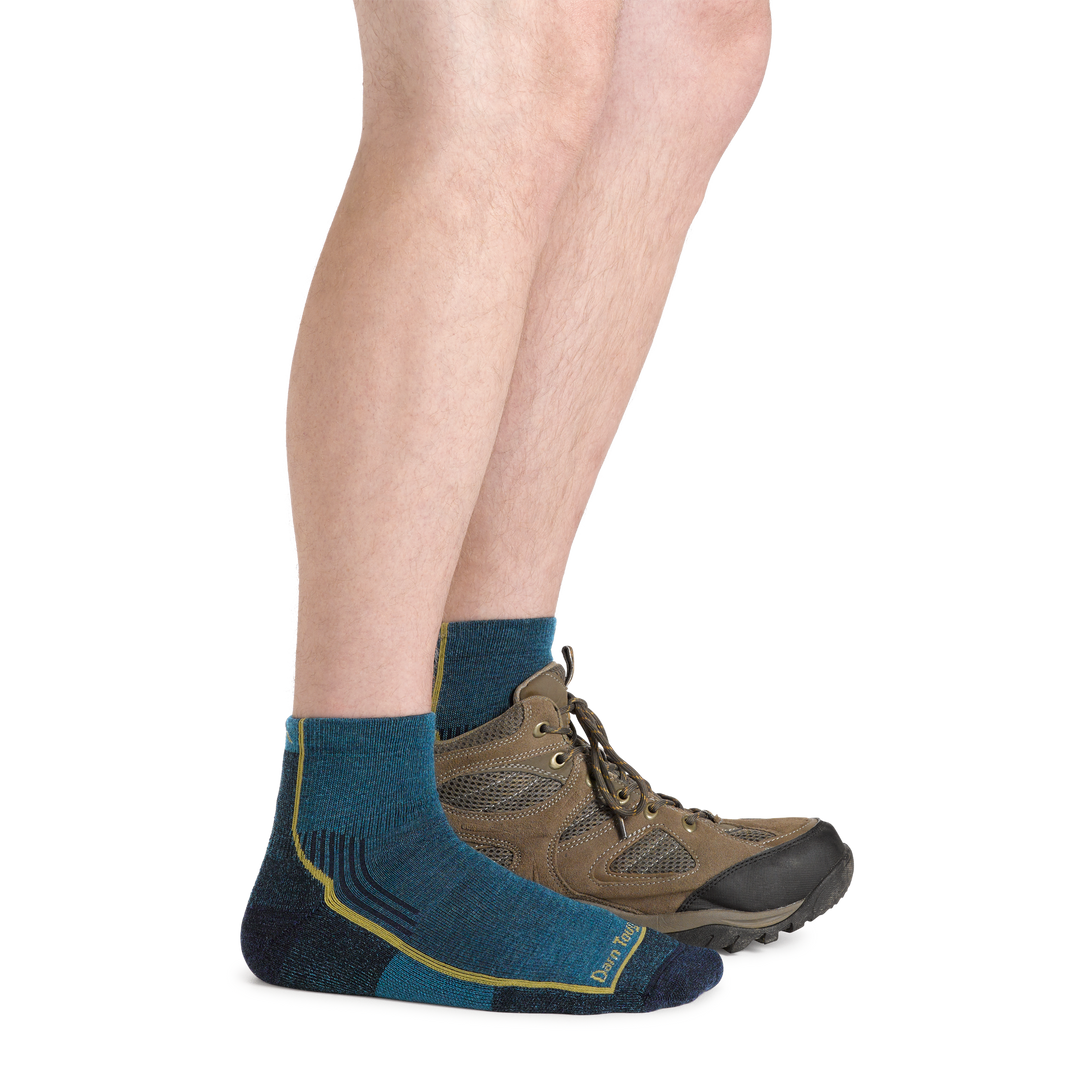Model wearing Men's Hiker Quarter Midweight Hiking Socks in dark teal and a hiking boot on one foot
