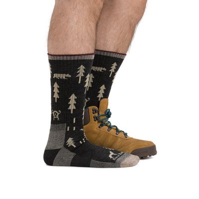 Man standing with front foot barefoot, back foot wearing a hiking boot and ABC Boot Midweight Hiking Socks in Black, showing height of socks is approximately mid-shin.