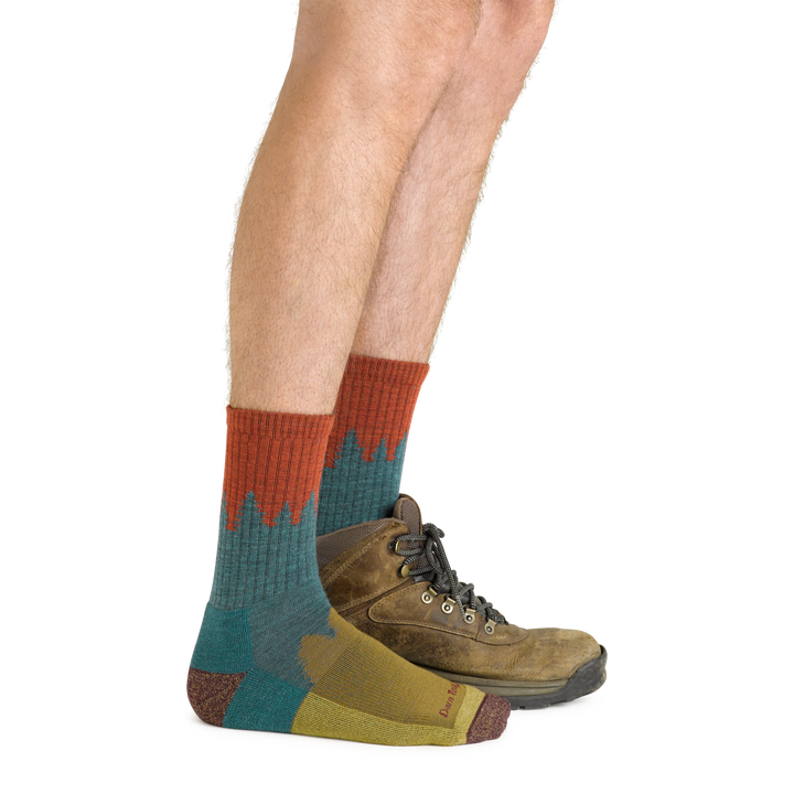 Side shot of model wearing the men's number 2 micro crew hiking sock in teal with a brown boot on his left foot