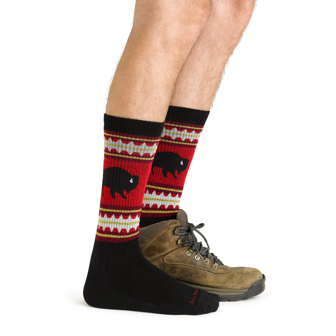 Side studio shot of model wearing men's vangrizzle boot hiking sock in black with brown hiking boot on left foot