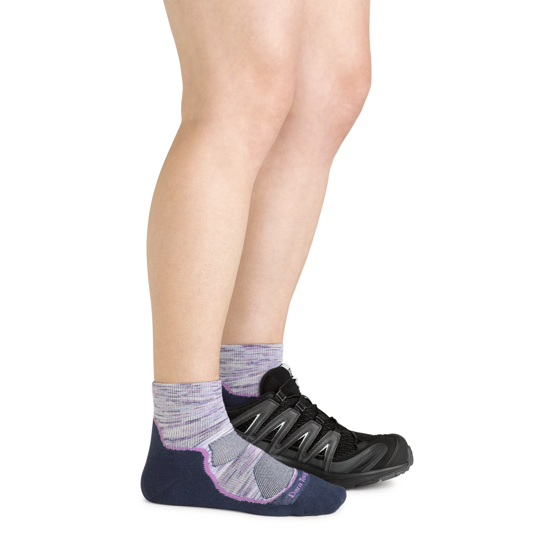 Model wearing the women's light hiker quarter hiking sock in cosmic purple with a black sneaker on her left foot