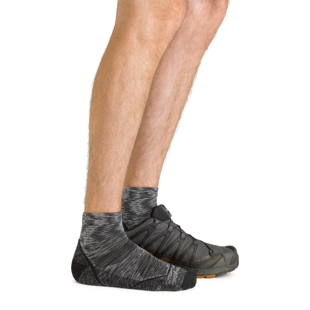 Side shot of model wearing the men's light hiker quarter hiking sock in space gray with a gray shoe on his left foot