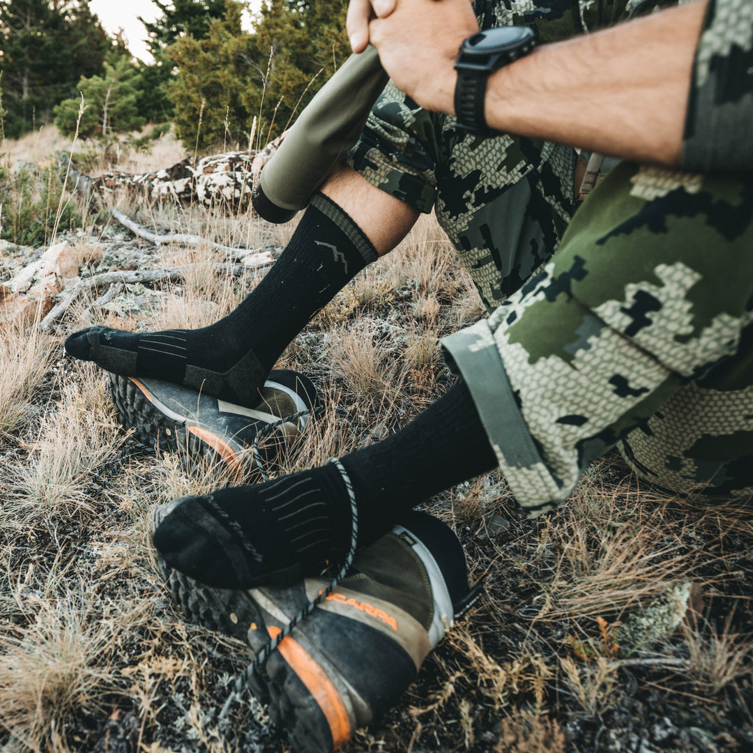 A hunter sitting on the ground with his feet resting on his boots wearing darn tough socks for hunting, Lifestyle Image