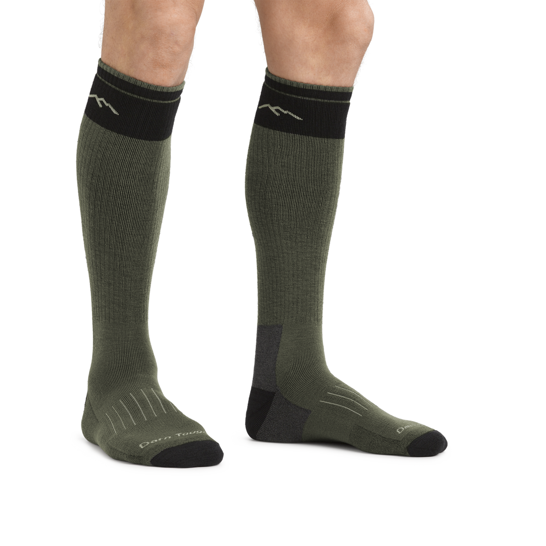 Man standing barefoot against a white background wearing Hunter Over the Calf Heavyweight Hunting Socks in Forest