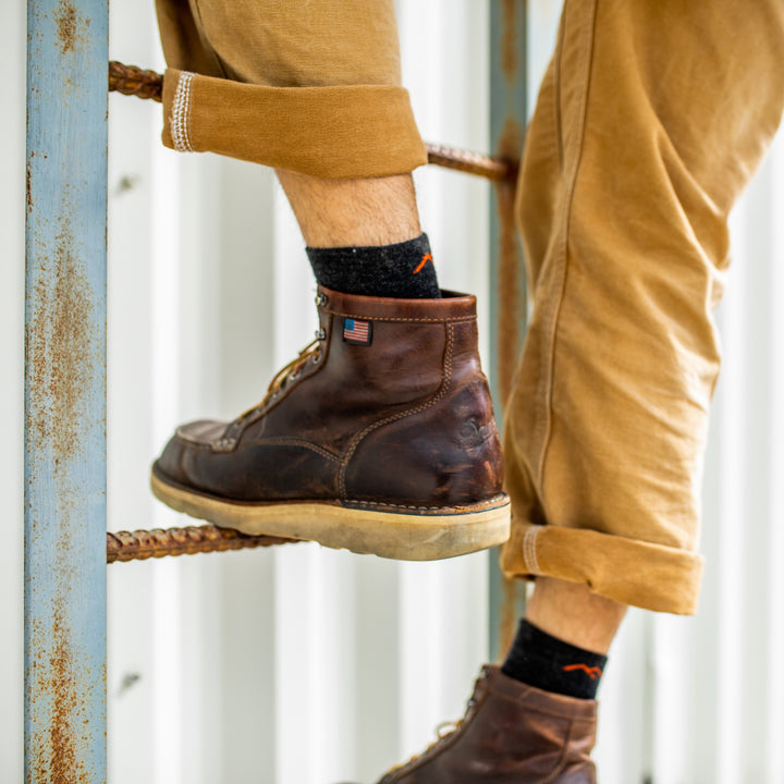 Close up shot of the back of a model climbing a ladder in brown work shoes wearing the men's steely quarter work sock