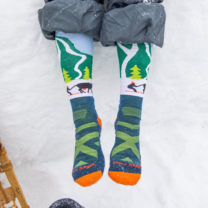 Close up shot of kids feet in snow wearing the Pow Cow socks and snowpants.