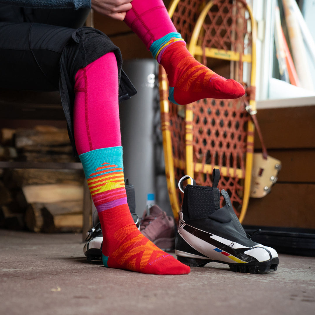 Close up shot of woman putting on Lillehammer nordic socks, getting ready to lace up her nordic ski boots.