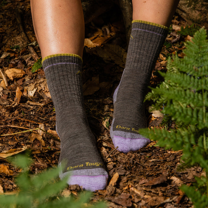 Close up lifestyle shot of model sitting in the woods next to some ferns in her hiker socks in Taupe.