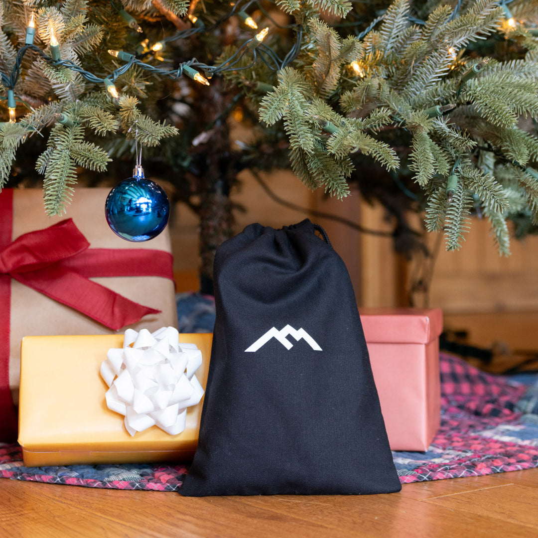 Gift bag under a tree with presents around it 