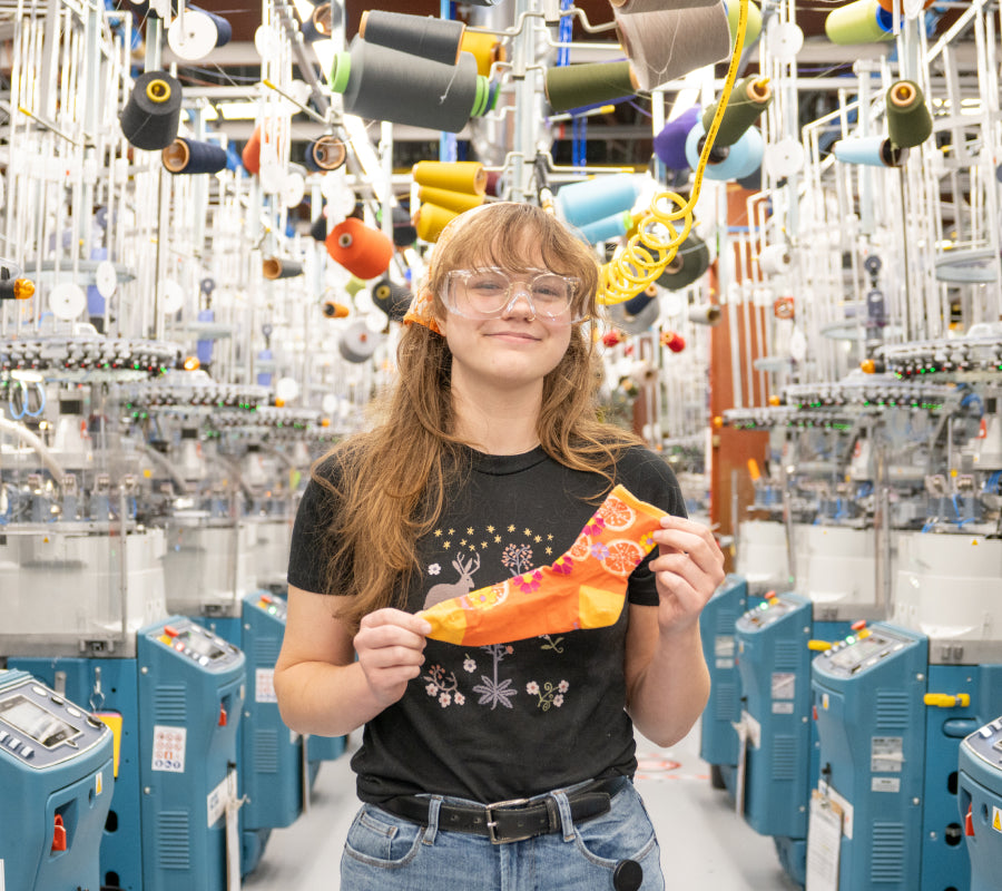 Kendra at the Mill holding up her favorite sock, the Fruit Stand in orange