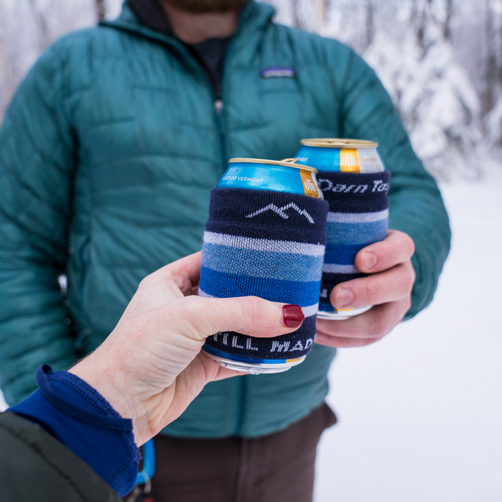 Two people holding two beverages with the blackberry koozie on them