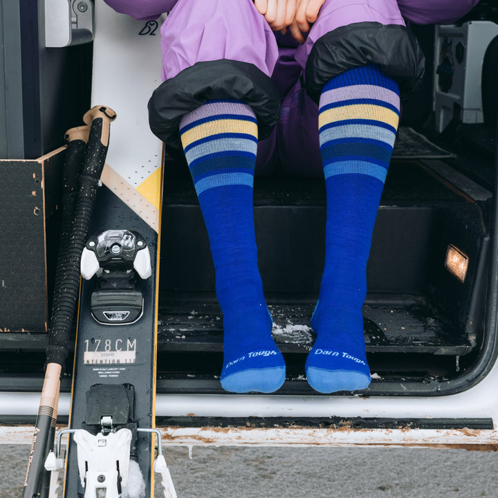model sitting on bus steps with skis wearing the snowburst in marine colorway