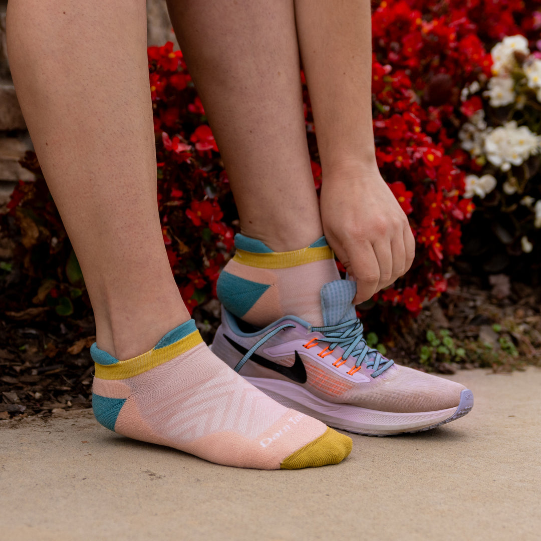 model image putting on running shoes wearing 1047 Limited edition no show in dusty rose.