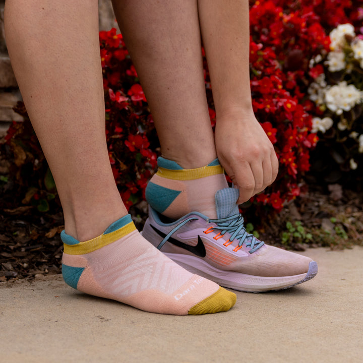 model image putting on running shoes wearing 1047 Limited edition no show in dusty rose.
