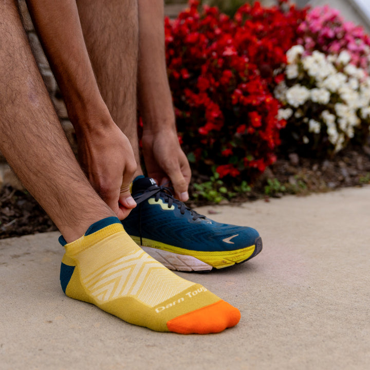 Model putting on running shoes and front foot wearing the 1039 Limited edition no show in gold