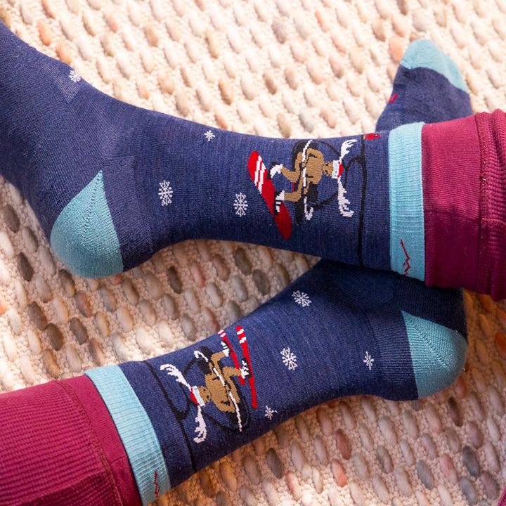 image of the moose on the loose on model showing both side of sock moose on ski lift one with snowboard one with ski