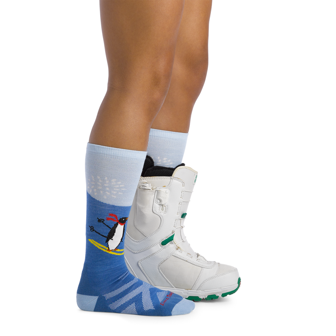 Image of model wearing 3808 Kids penguin peak ski and snowboard socks and a snow boot on one foot